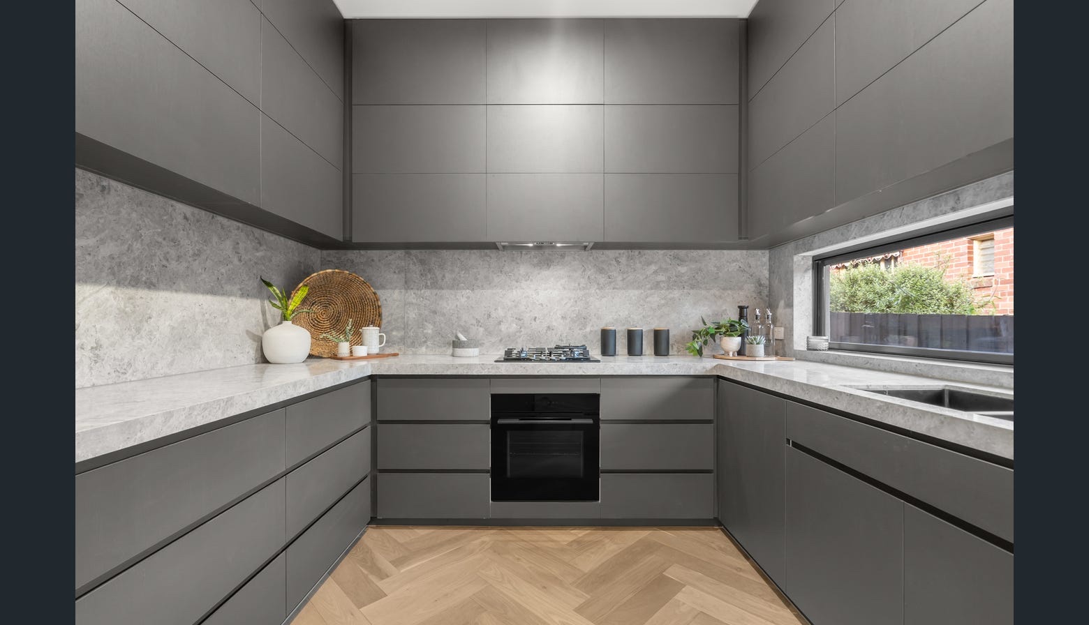 Completed dark kitchen with warm herringbone flooring